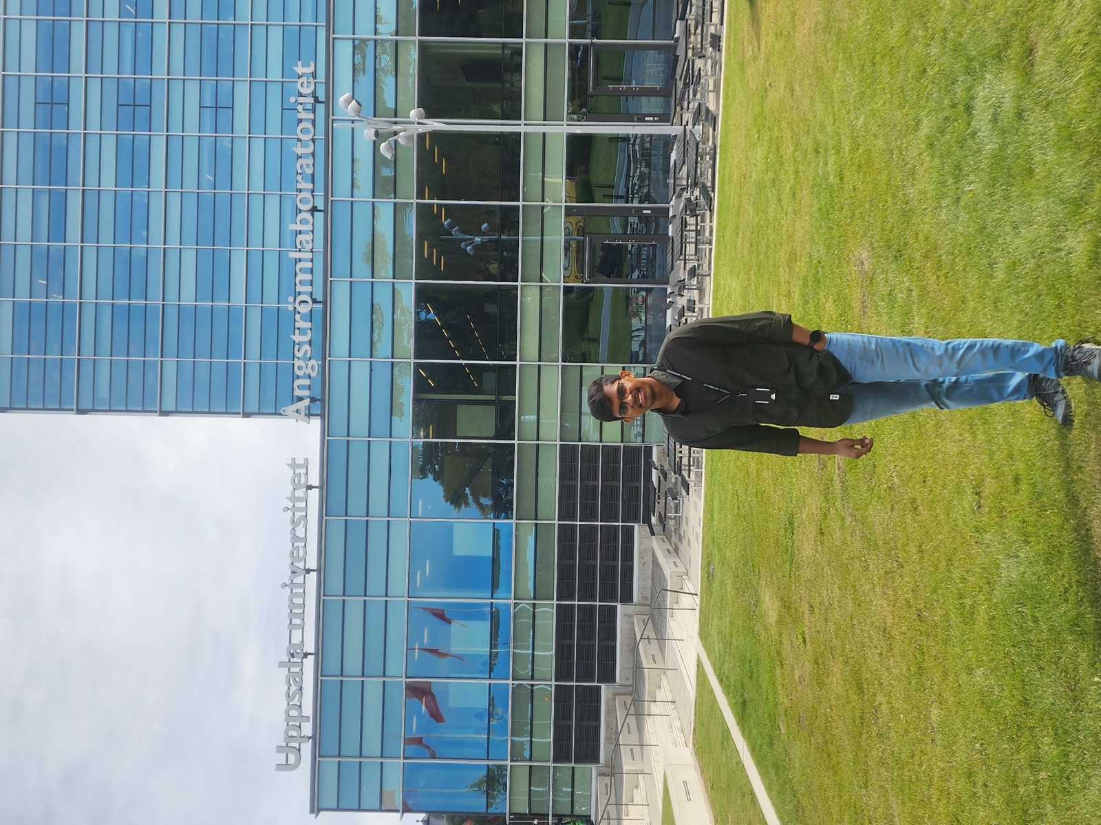 Rishit Reddy standing on the lawn in front of the Ångström Laboratory at Uppsala University