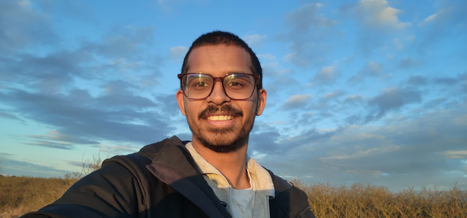 Rishit Reddy Palle smiling outdoors against a blue sky